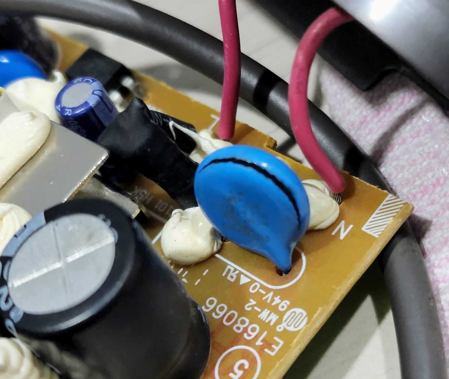 A cracked blue disc component sits among wires and capacitors on a circuit board.