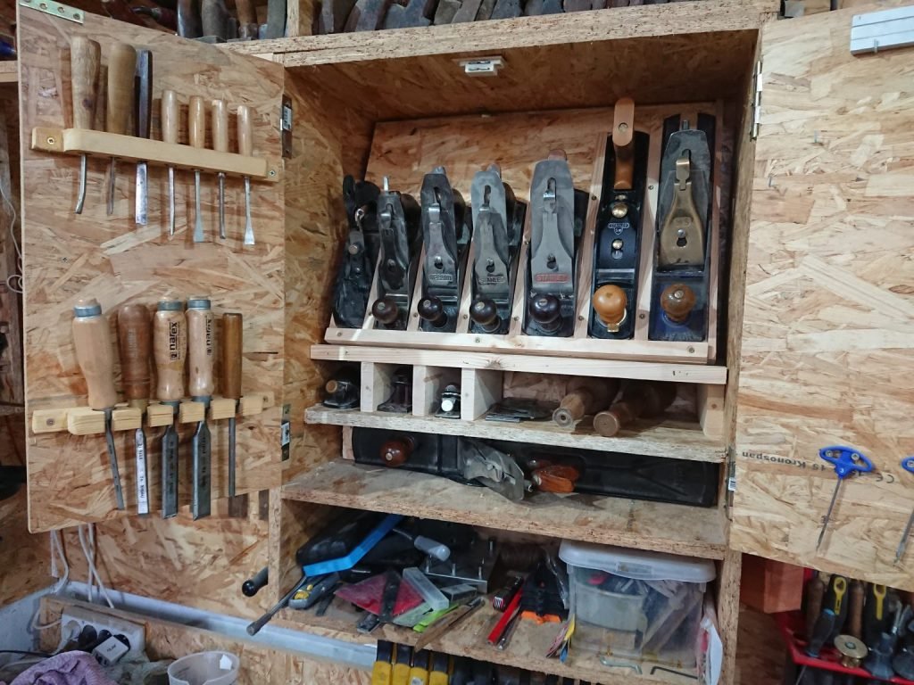 An open cabinet with woodworking tools arranged inside.