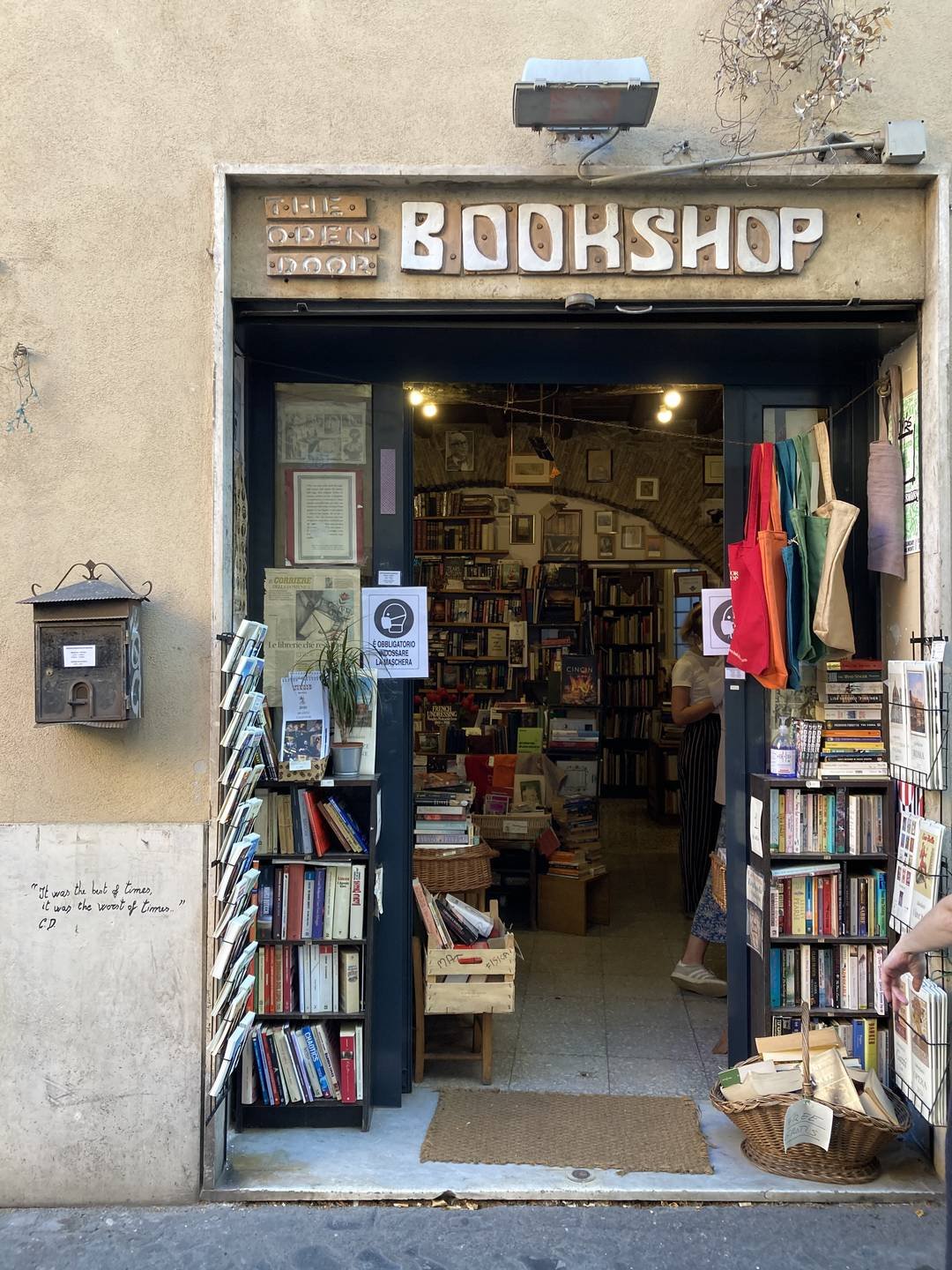 A small bookshop window set into a stone wall, its shelves packed with books and prints.