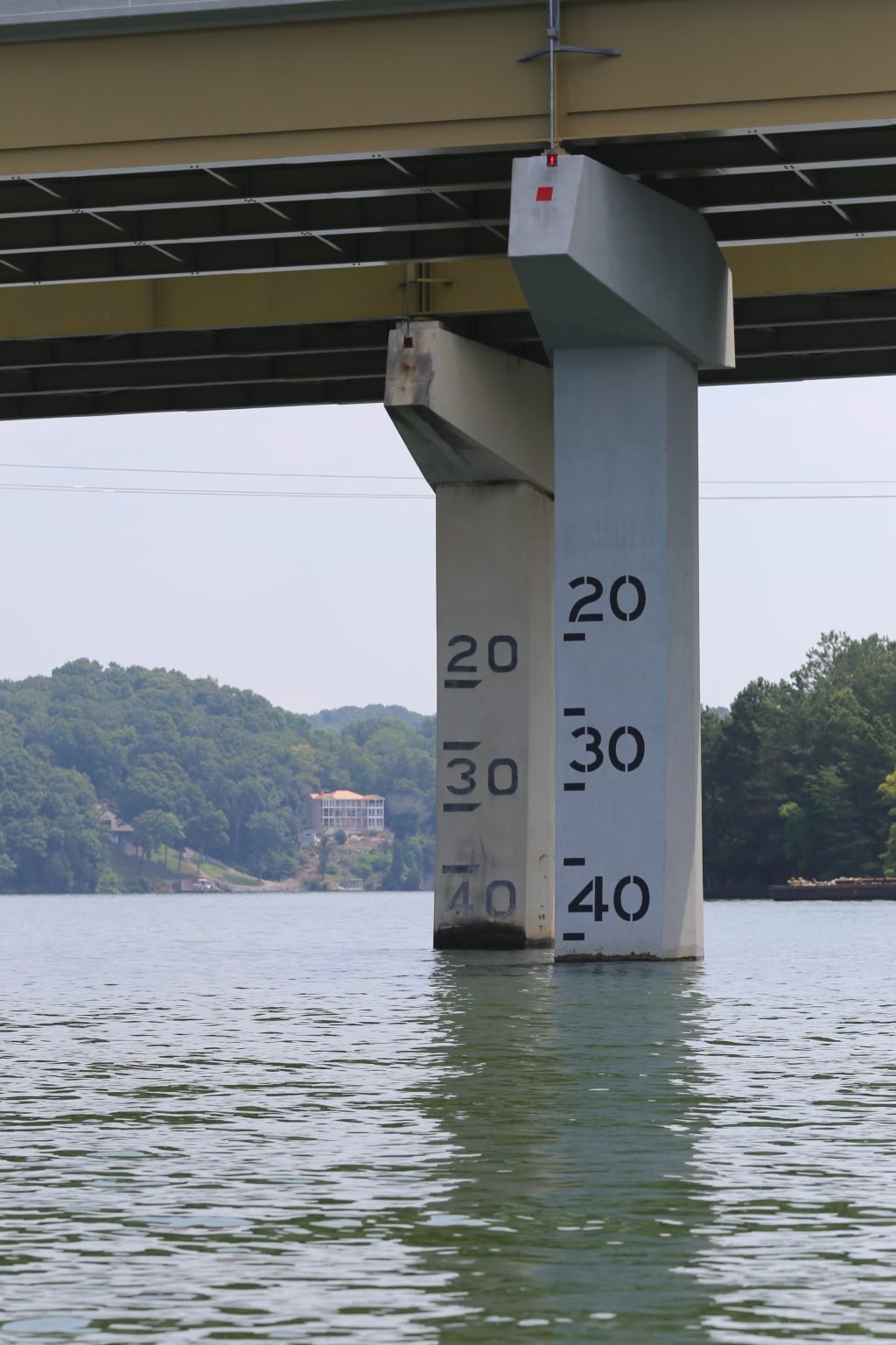 Bridge piers stand in water, with painted clearance markings on one pillar.