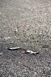 A broken cassette and loose tape lie on sunlit asphalt.
