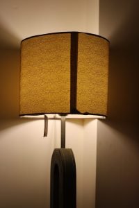 A lit table lamp casts warm light through its textured shade.