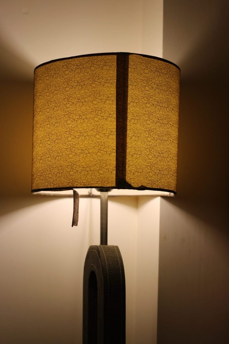 A lit table lamp casts warm light through its textured shade.