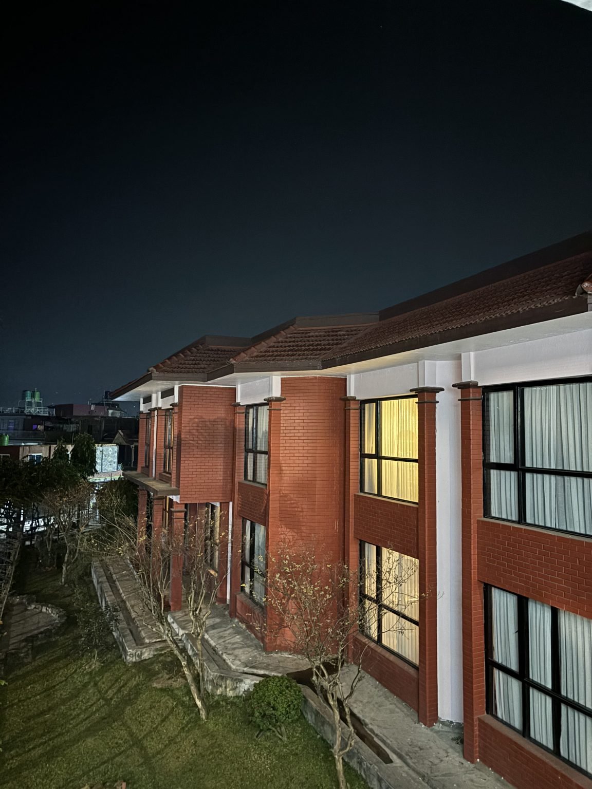 Curtained windows glow in a red-brick building beneath a dark sky.
